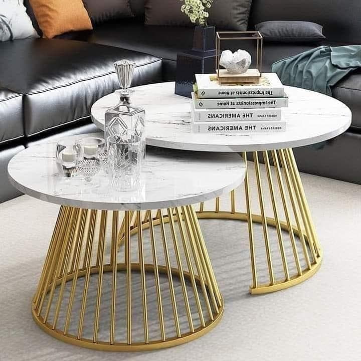 Round marble-top coffee tables with gold metal bases in a modern living room.
