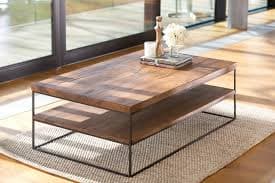 Rectangular wooden coffee table with metal frame in sunlit lounge area.