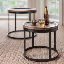 Round wooden top side tables with black metal frames in a lounge setting.