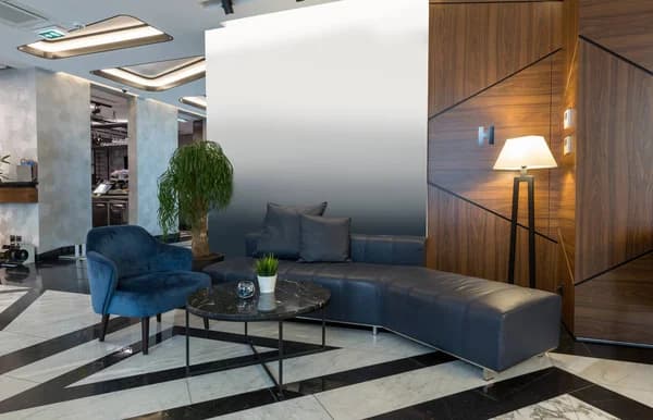 Round marble coffee table with black sofa and blue chair in a hotel lounge.