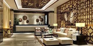 Luxurious hotel lobby with geometric wooden panels, beige seating, and ambient lighting.