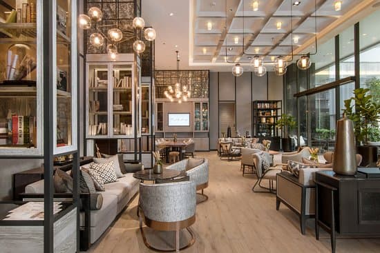 Modern hotel lounge with bookshelf decor, soft seating, and pendant lighting.