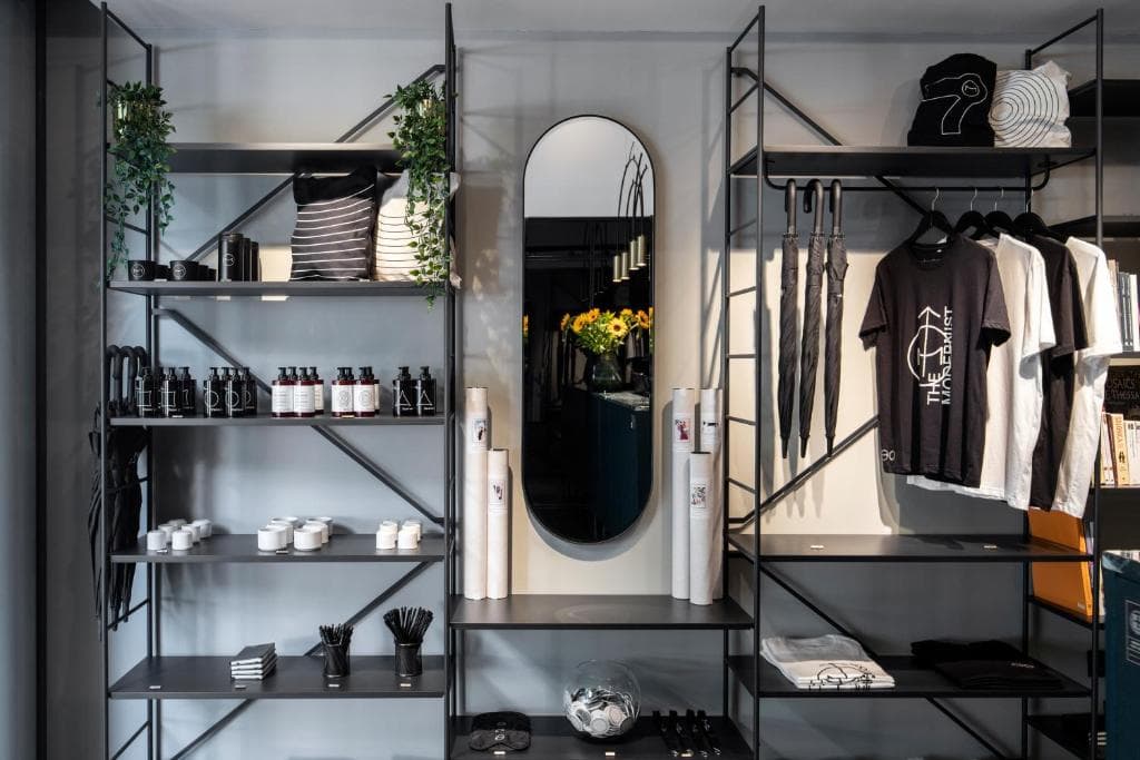 Open metal shelving with clothes, decor, and amenities around a central mirror.