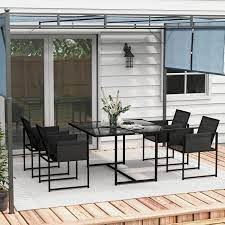 Modern black outdoor dining set with eight chairs on a wooden deck outside a white house with glass doors and canopy.
