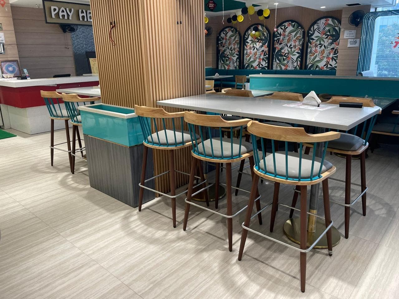 High seating arrangement with teal-accented bar stools around a large table in a vibrant restaurant interior.