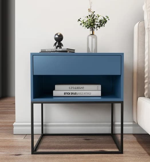 Blue modern side table with open shelving and a drawer, supported by a sleek black metal base, styled with books and decor.
