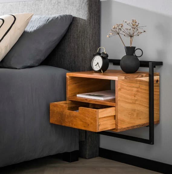 Wall-mounted wooden bedside table with black metal frame, open shelf, and drawer, styled with a clock and minimalist decor.