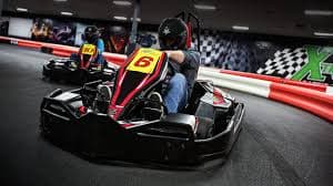 Two go-kart racers navigating a sharp indoor track corner with speed and focus.