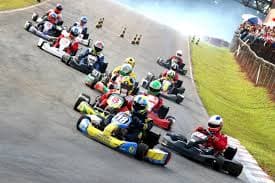 A large group of go-kart racers competing on a curved outdoor track.