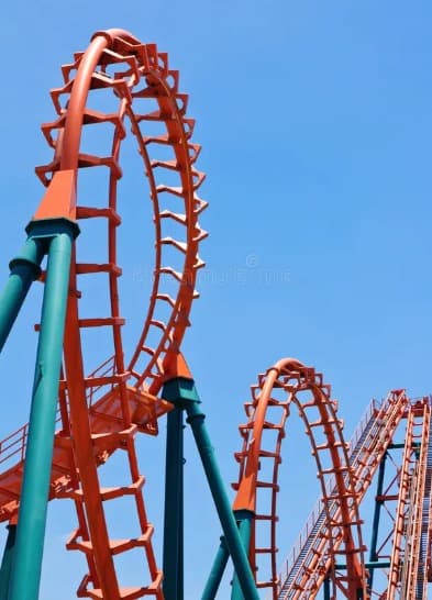 Bright orange roller coaster loops supported by teal pillars, set against a clear blue sky.