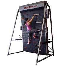 Woman climbing on a vertical rotating treadmill wall used for fitness and training.