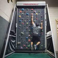 Man climbing on a Treadwall with colorful holds, used for continuous climbing workouts.