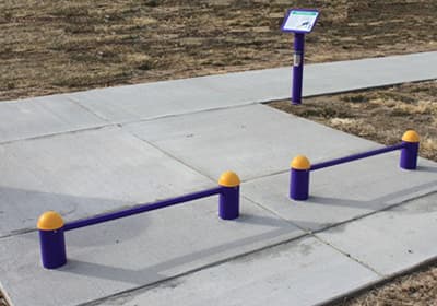 Outdoor push-up bars with purple poles and yellow caps on a concrete surface, designed for fitness and exercise.