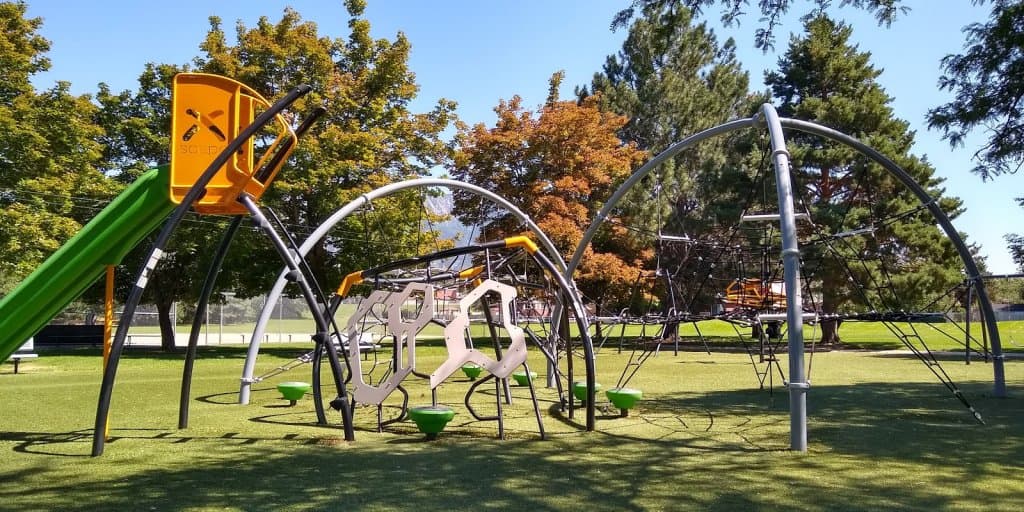 Modern playground with climbing ropes and curved structures, promoting interactive and adventurous play.