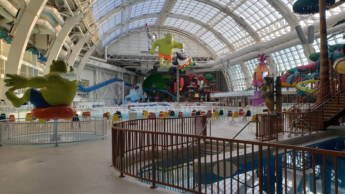 Indoor water park with colorful slides, large character statues, and sturdy railings complementing the vibrant theme.
