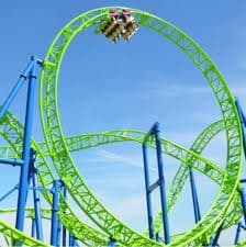 Bright green roller coaster track with a loop against a clear blue sky.